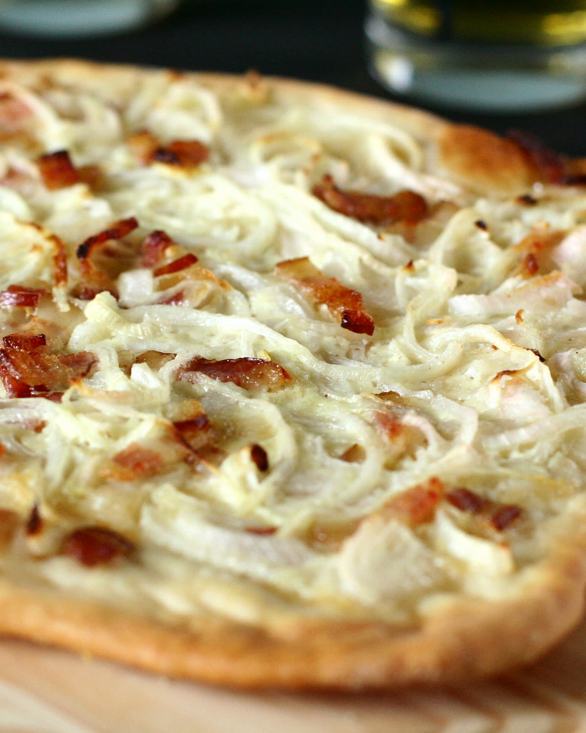 Une tarte flambée alsacienne servie sur sa planche de bois