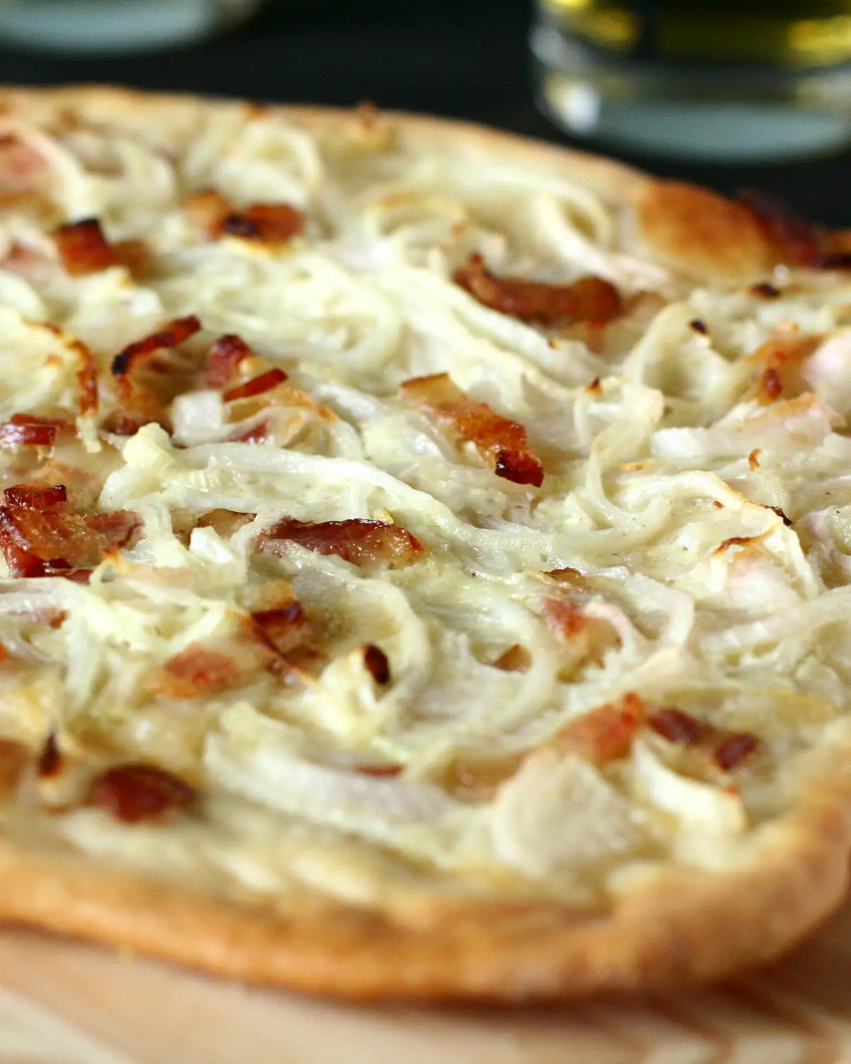 Une tarte flambée alsacienne servie sur sa planche de bois