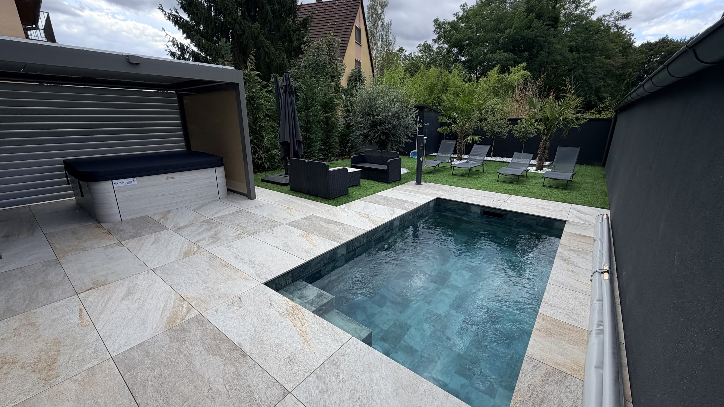 La large terrasse en pierre le long de la piscine